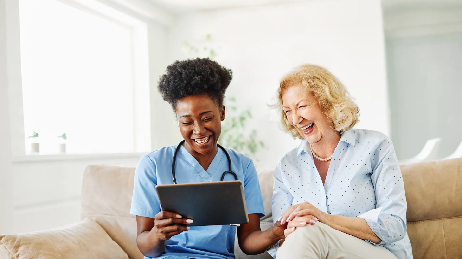 Two women sitting on a couch looking at a laptop