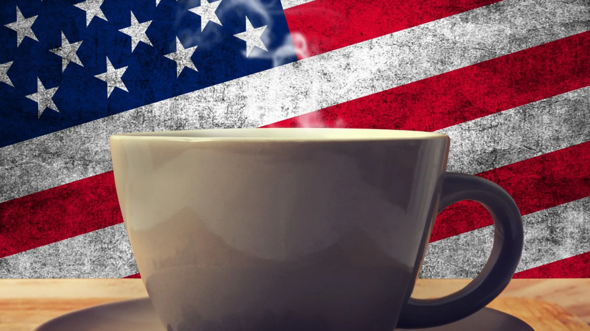 A steaming coffee cup on a wooden table with an American flag background.