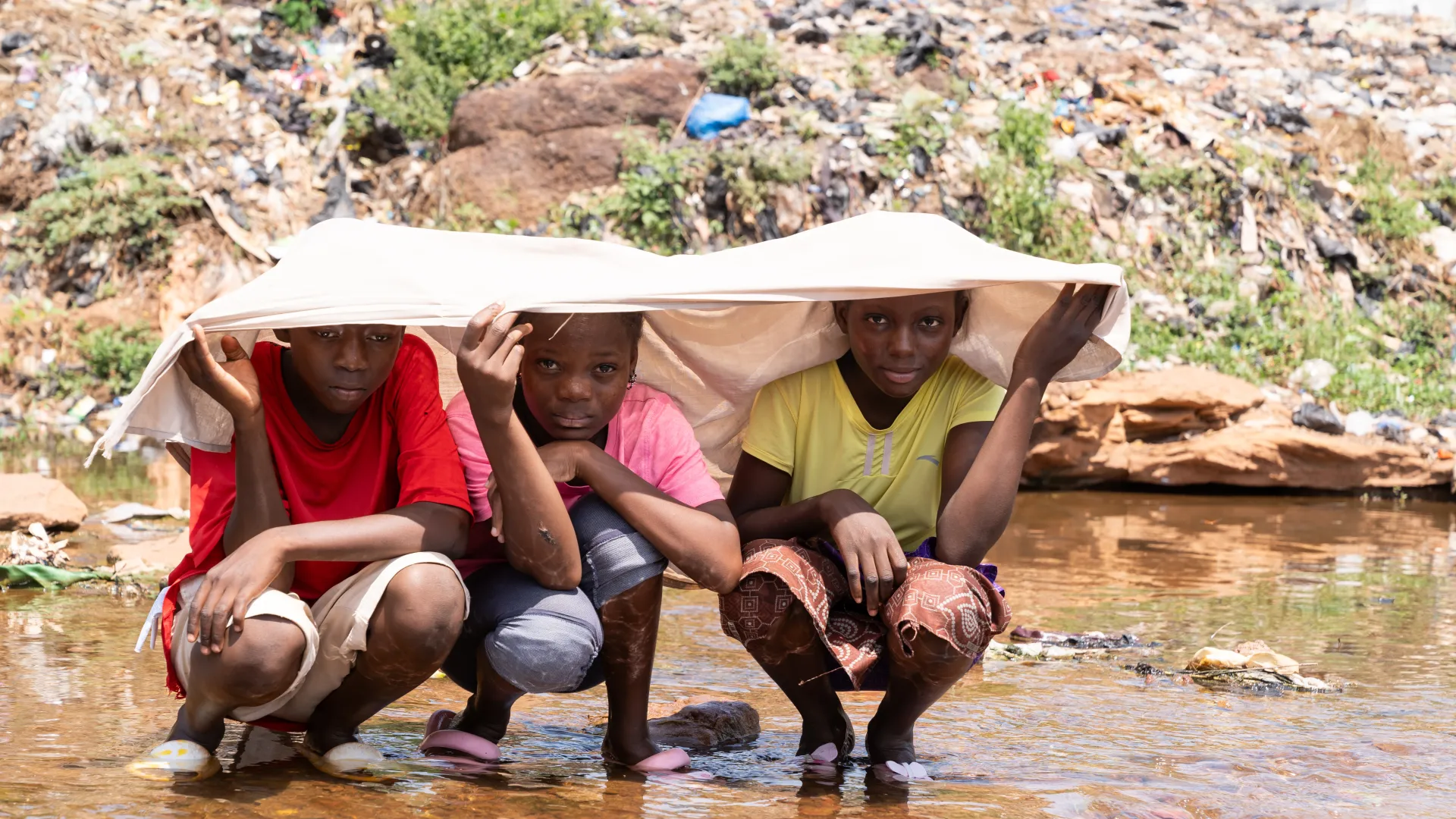 a group of people sitting in a shallow river