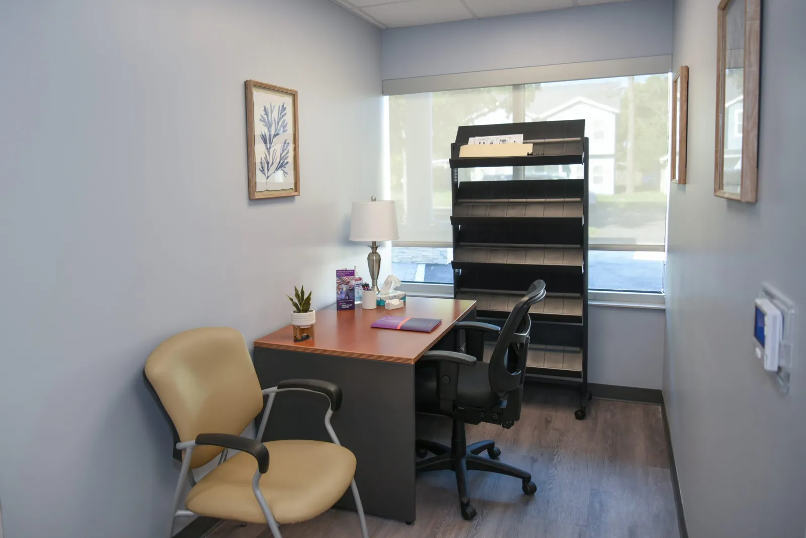 a desk with a chair and a lamp in a room with a window