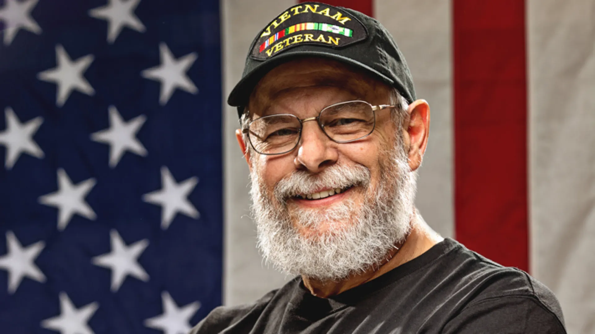 a man smiling in front of a flag