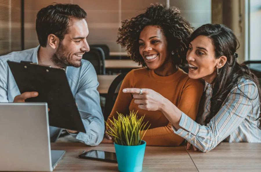 a group of people sitting at a table looking at a laptop